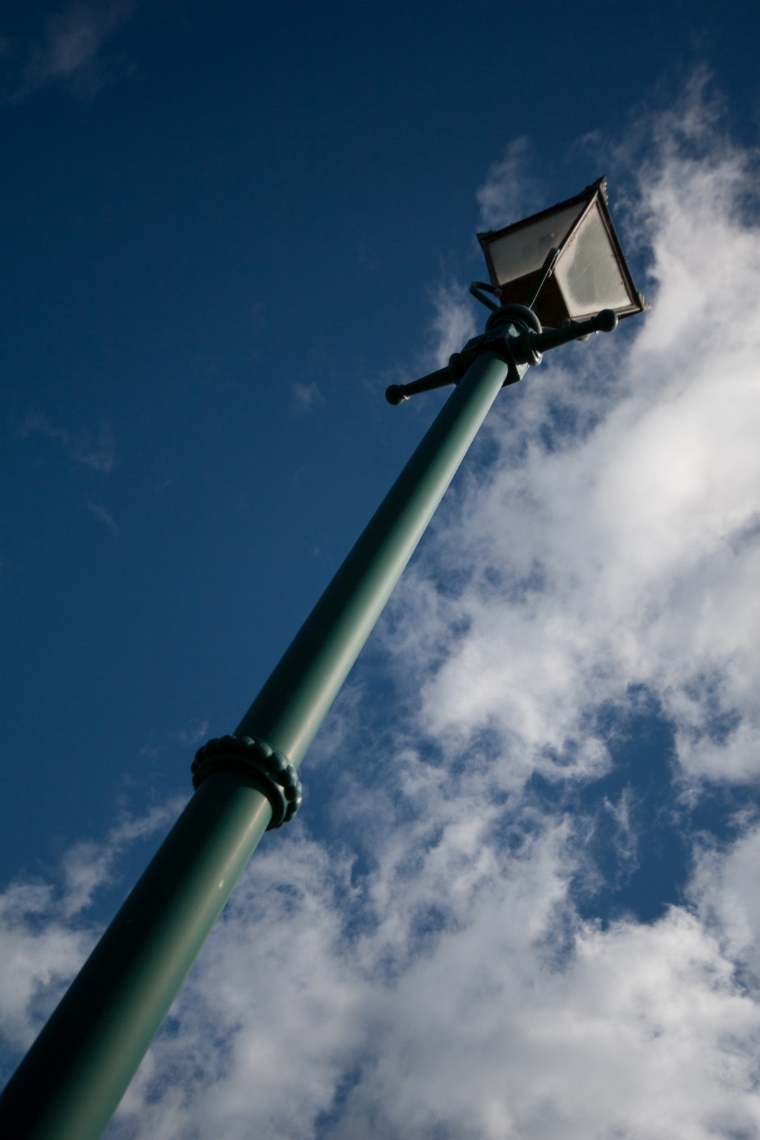 green lamp post against the blue sky