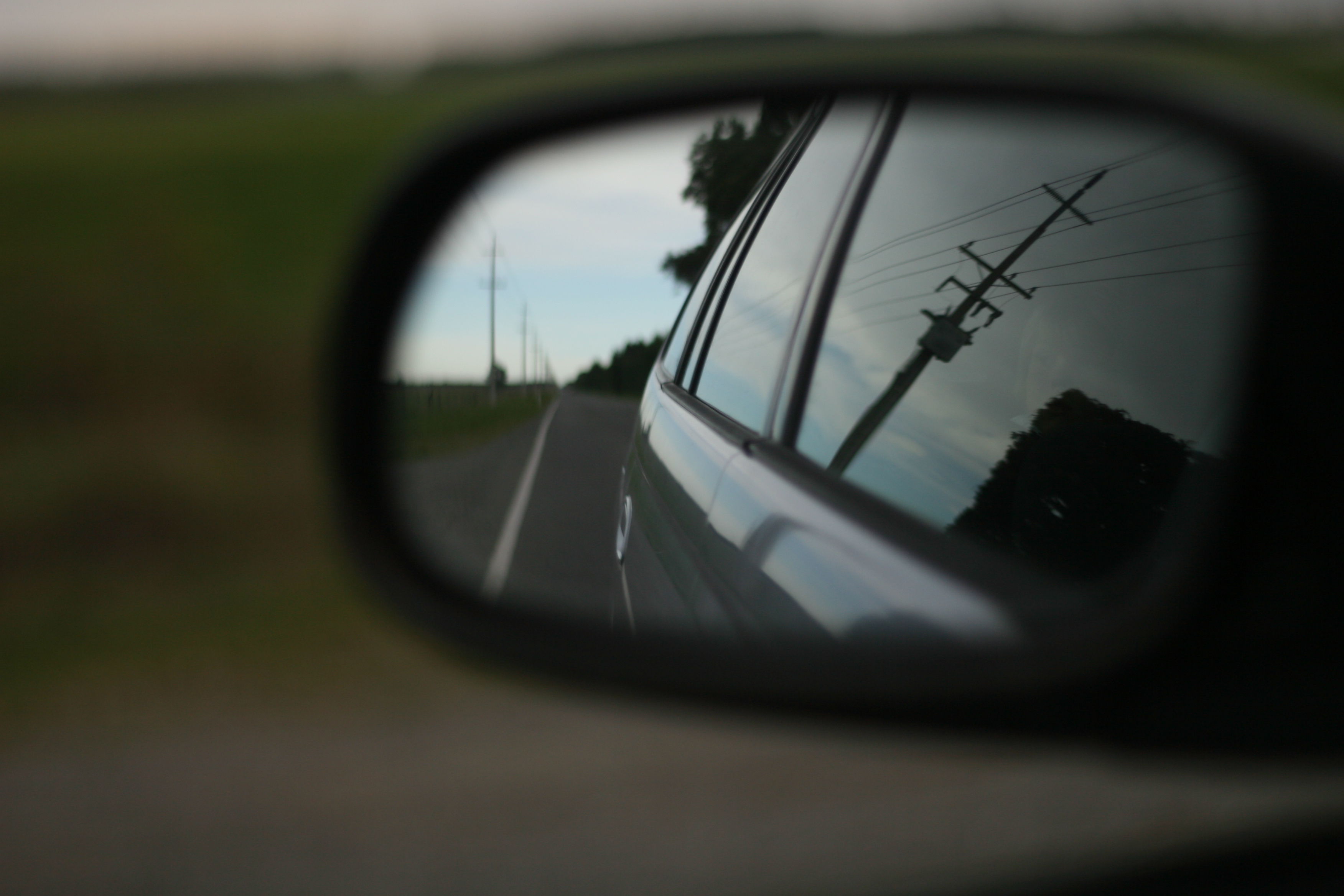 looking through a car side mirror with a power pole reflected on the car window