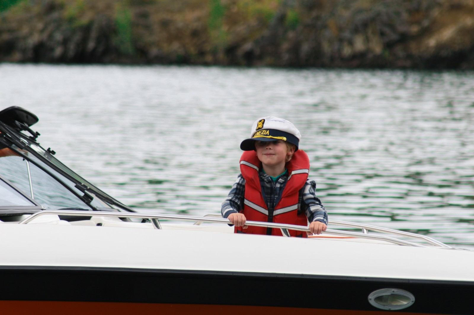 boy on a boat with a captains hat crooked on head