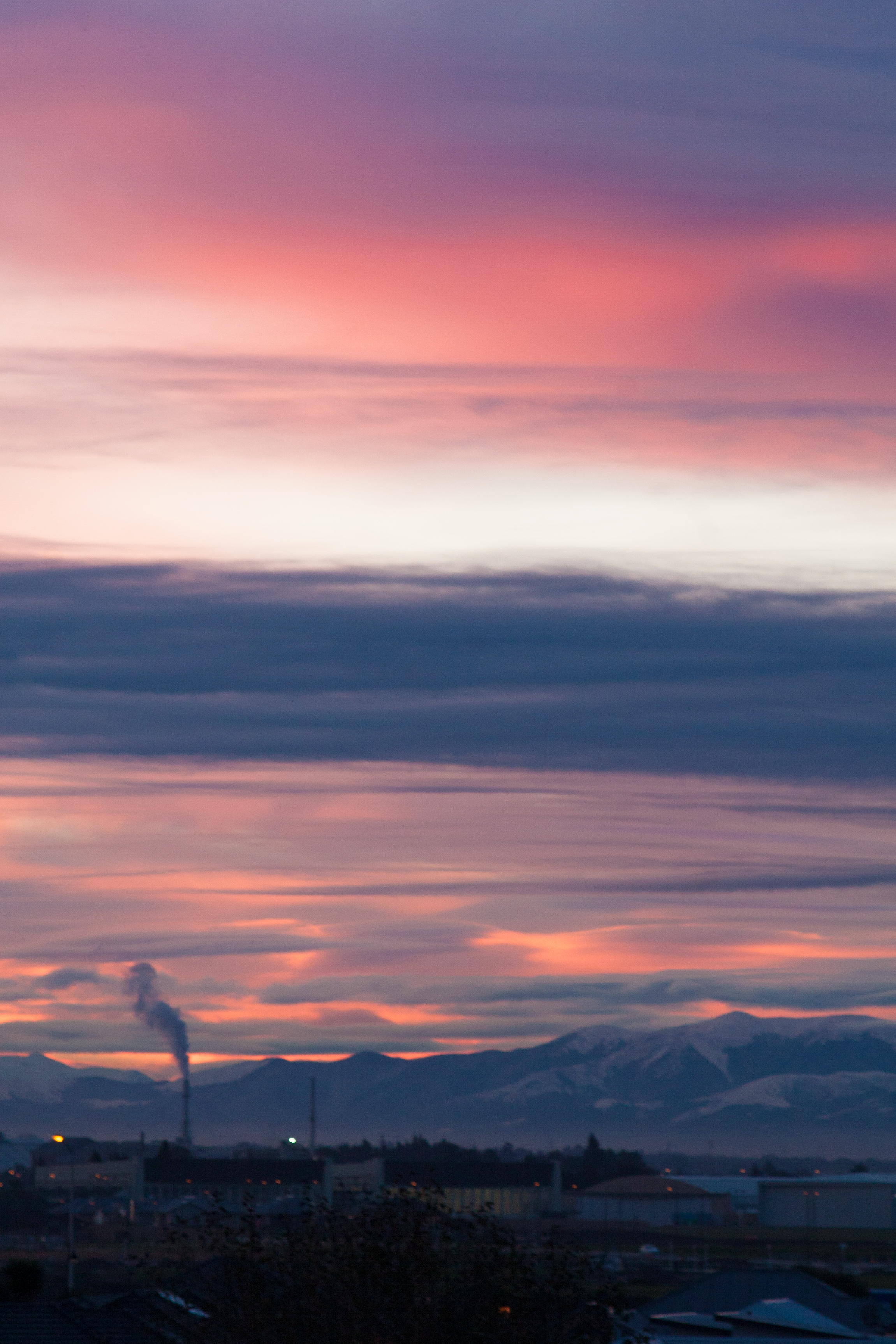 smoke stack against mountains and a pink sunset